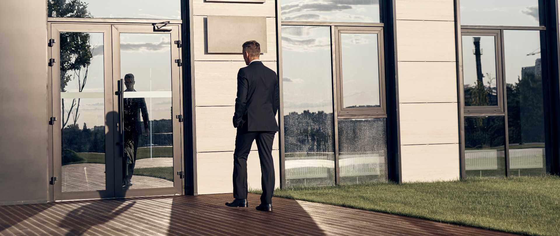 Formal agent standing outside a modern building, linked to real estate agency work.